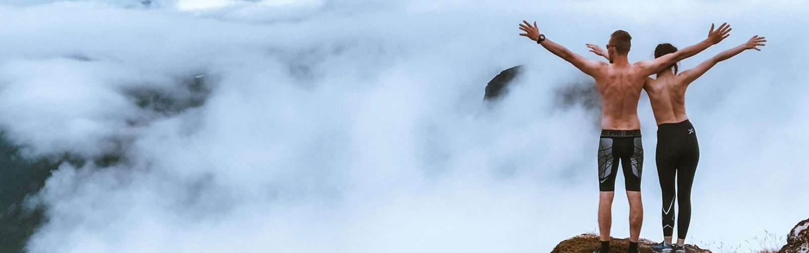 pexels photo 1819657 1819657 Two hikers stand on a rocky cliff, embracing the expansive mountain view and clouds, symbolizing freedom and exploration.
